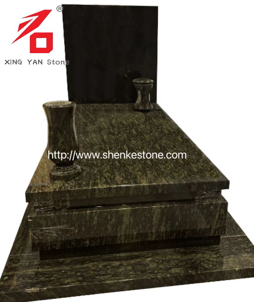 Olivegrønn granittmonument og støttende svarte steintabletter, vaser og lykter